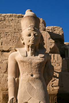 Ancient pharaoh statue holding symbols against a blue sky at Karnak Temple in Luxor Egypt