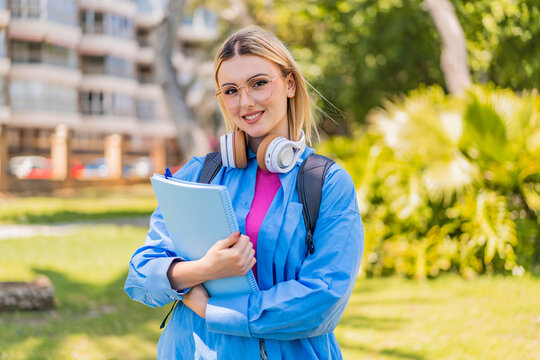 Young pretty blonde woman at outdoors holding a notebook