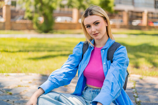 Young pretty blonde woman at outdoors with happy expression