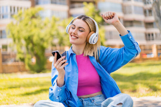 Young pretty blonde woman at outdoors using mobile phone