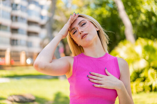Young pretty blonde woman at outdoors With glasses and tired
