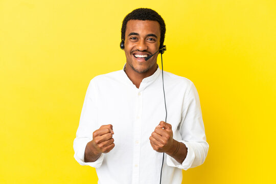 African American Telemarketer man working with a headset over isolated yellow background celebrating a victory in winner position