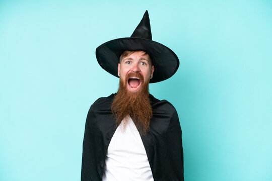 Young wizard in halloween isolated on blue background with surprise facial expression