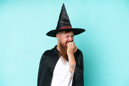 Young wizard in halloween isolated on blue background having doubts