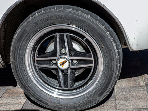 Detailed view of Targa four spoke alloy wheel with Yokohama tire on a vintage car in a sunny outdoor setting