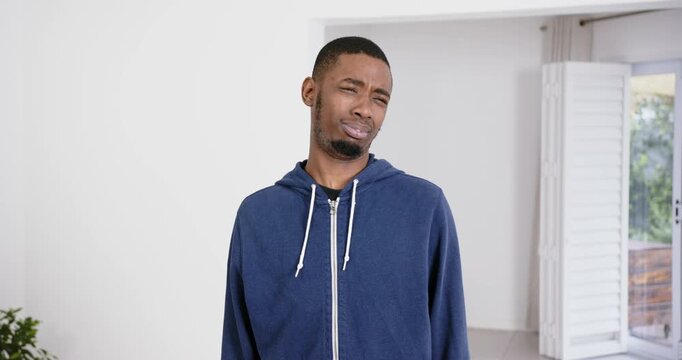 High speed photography for dynamic scenes, man in blue hoodie making confused expression in bright i
