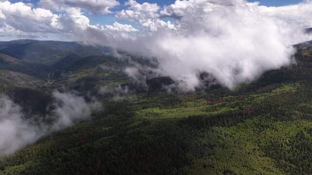 Aerial of forested mountains and rolling clouds over Carson National Forest near Sipapu New Mexico in Taos County during a cloudy afternoon