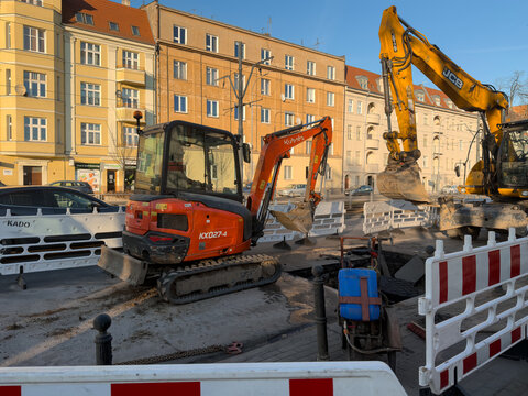 Poznan, Poland - March 3, 2026: Kubota and JCB excavators performing road maintenance on a residential urban street with barriers during a sunny day for industrial development work