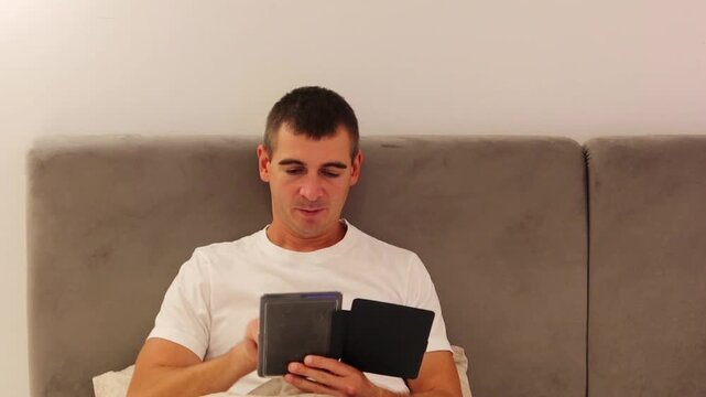 Man Reading an E-Book in Bed in the Evening at Home