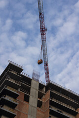 Construction crane and pallet with bricks above the top floor of a house under construction © 201122