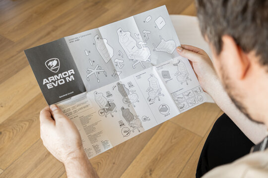Poznan, Poland - March 4, 2026: Cougar Armor Evo M gaming chair assembly guide held by a man, showing steps for furniture construction to support ergonomic home office work projects