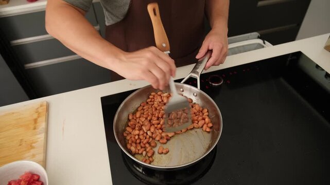 Professional chef preparing a bean dish in a frying pan on an induction stove