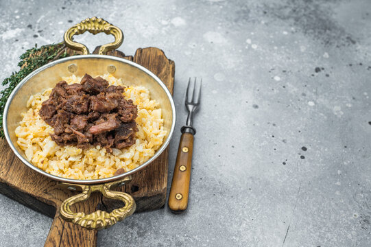Traditional kavurma with roasted meat chunks atop seasoned pilav, emphasizing Maillard browning, grain morphology and overhead plating.