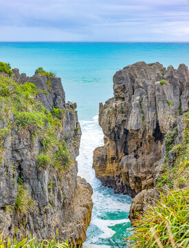 Blick durch geschichtete Kalksteinfelsen auf das t&uuml;rkise Meer bei den Pancake Rocks, Punakaiki, Neuseeland