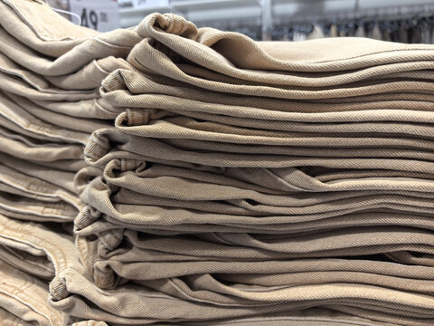 Neatly folded beige trousers arranged in a retail store display