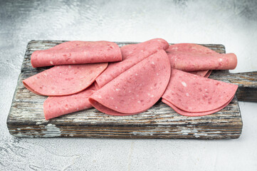 Soft textured beef salam slices on weathered wooden board with thyme sprigs on bright studio background ideal for gourmet food prep and stock imagery © Mironov