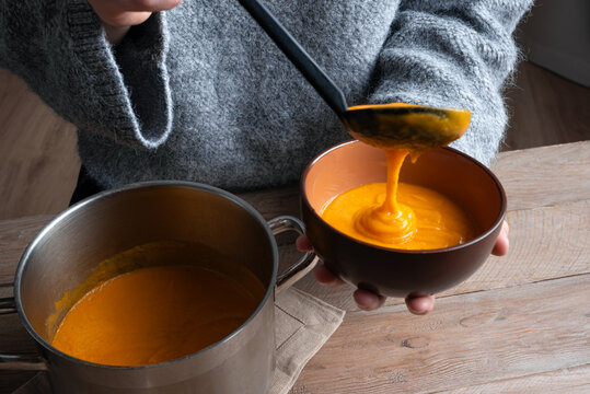 Person's hands ladling soup into bowl