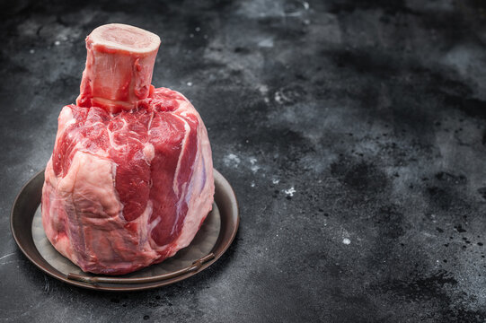 Fresh raw beef shank knuckle whole cut with bone in rustic tray on gray background ingredient for osso buco and slow cooking