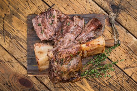 Tender slow cooked veal ossobuco with juicy meat pieces bone marrow herbs on wooden background