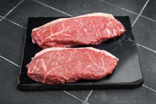 Raw beef culotte steaks also called picanha or rump cap on slate board with herbs, minimal rustic food concept