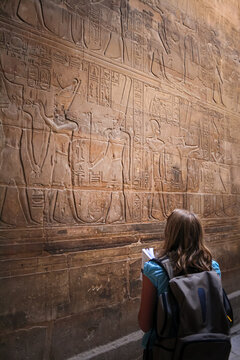 Tourist examining ancient hieroglyphs carved into a wall at Luxor Temple in Luxor Egypt
