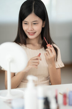 Beautiful Asian woman sit in front of a mirror. face of a healthy woman applying cream and makeup. Advertisement for skin cream, anti-wrinkle, baby face, whitening, moisturizer, tighten pores serum