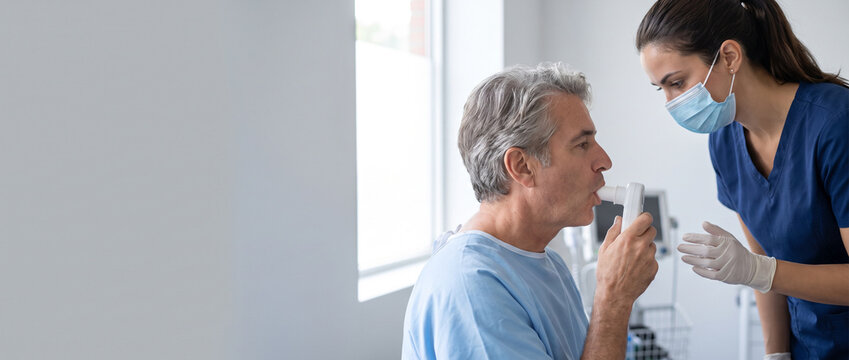 Adult patient completing lung function test with healthcare professional using spirometry equipment, representing respiratory health assessment, pulmonary testing and clinical patient care.