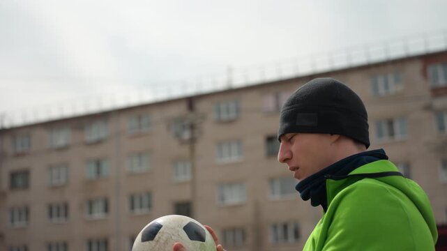 player intercepts airborne ball, man skillfully catches flying soccer, athlete in city catches ball swiftly, closeup of male player reaching for ball amid city apartment surroundings