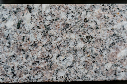 Close-up of rough granite stone surface with pink, white and black mineral grains