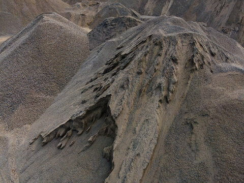 Aerial View of a Large Aggregate Stockpile with Distinctive Dune-Like Surface Textures at a Mining Site in Indonesia. Industrial Landscape and Abstract Geological Texture Viewed from Above.
