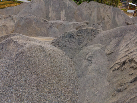 Aerial View of a Large Aggregate Stockpile with Distinctive Dune-Like Surface Textures at a Mining Site in Indonesia. Industrial Landscape and Abstract Geological Texture Viewed from Above.