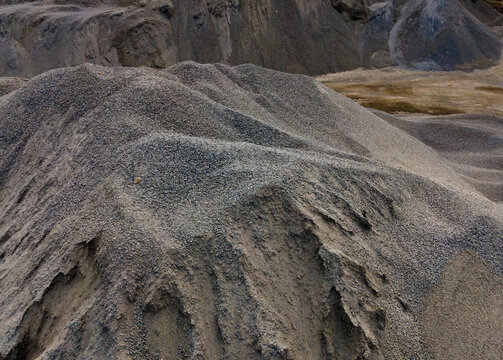 Aerial View of a Large Aggregate Stockpile with Distinctive Dune-Like Surface Textures at a Mining Site in Indonesia. Industrial Landscape and Abstract Geological Texture Viewed from Above.