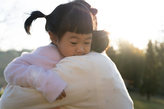 Happy Mother hugging and carry daughter playing together outdoors Family Childhood development and growth with love for her Mom's concern Happy baby's dream