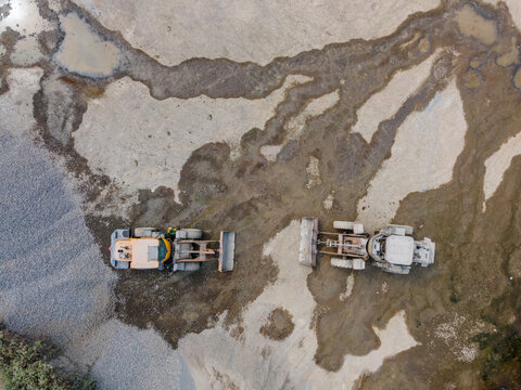 Wheel Loader Working in a Rock and Sand Quarry in Indonesia. Quarry Floor with Distinctive Ground Patterns Surround the Heavy Earthmoving Machine, Industrial Mining Site view from above.