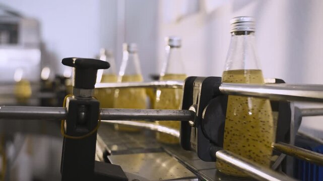 Juice in glass bottles on an automated conveyor belt in a modern beverage production facility line. Technology in the food and drink industry. Ready to drink fruit juice in a manufacturing factory. 