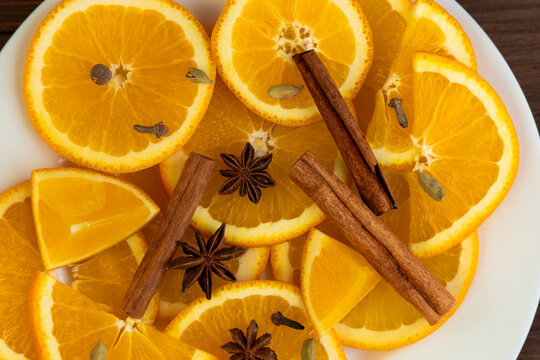 Slices of orange with spices arranged on a white plate in a kitchen setting