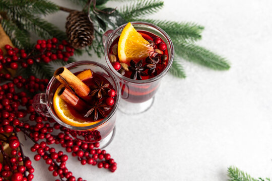 Warm mulled wine drinks with spices and fruits on a table with festive decorations