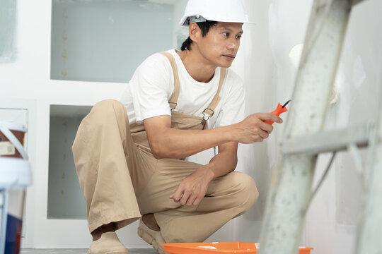 painter man, brush in hand for products to restore and paint the wall, indoor the building site of a house, wall during painting, renovation, painting, contractor, Architect, construction worker
