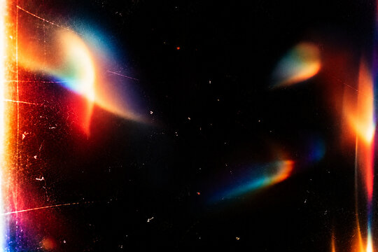 Abstract colorful light leak overlay on a deep black background, irregular soft-focus rainbow light leaks and glowing color blooms, vibrant red, orange, yellow, cyan, blue, magenta and subtle green to