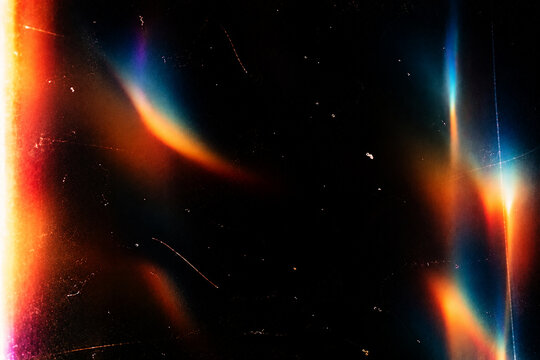 Abstract colorful light leak overlay on a deep black background, irregular soft-focus rainbow light leaks and glowing color blooms, vibrant red, orange, yellow, cyan, blue, magenta and subtle green to