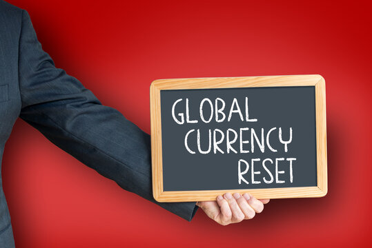 Businessman holding chalkboard with text global currency reset on red background