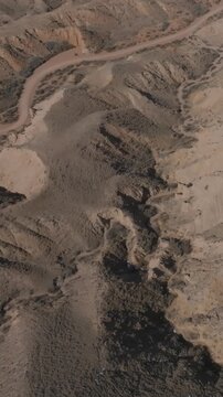Drone footage of arid badlands and winding dirt tracks in Skazka Canyon near Issyk-Kul Lake, Kyrgyzstan, remote mountain landscape