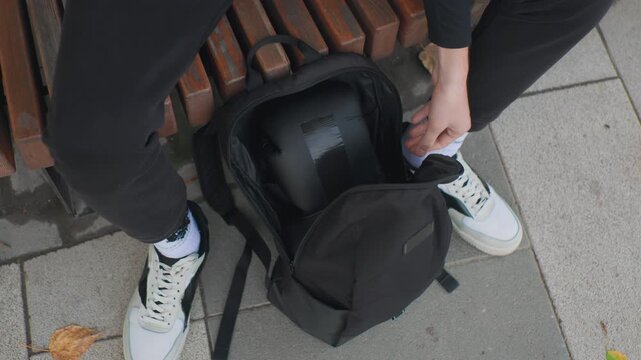 Cyclist organizing gear before starting journey, Male rider securing helmet in backpack prior to departure, Urban male cyclist double checking helmet straps and zippers before leaving