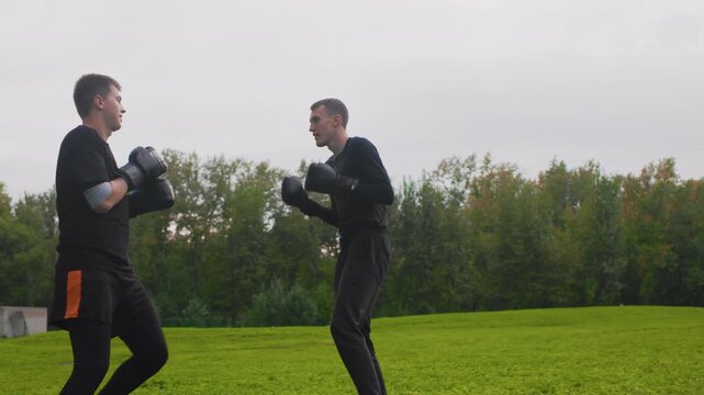 two caucasian men exchanging punches in open field, competitive bout simulation with rapid attacks and defensive blocks, aggressive combinations, evasive dodges and reactive counters, high energy