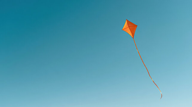 Single orange kite flying in a clear teal sky with large copy space