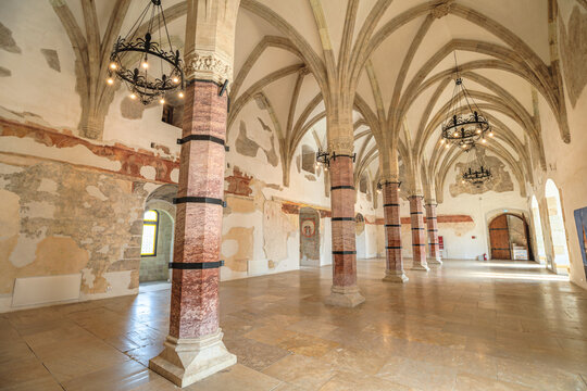 Corvin Castle's interior showcasing the vast great hall with multiple octagonal columns, impressive vaulted ceilings, and remnants of old frescoes on ancient walls in Hunedoara, Romania Transylvania