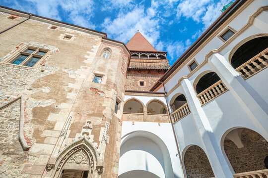 Corvin Castle displaying stunning gothic architecture in Transylvania with intricate stone details, arched balconies, and towering medieval structures under a clear blue sky in Hunedoara, Romania