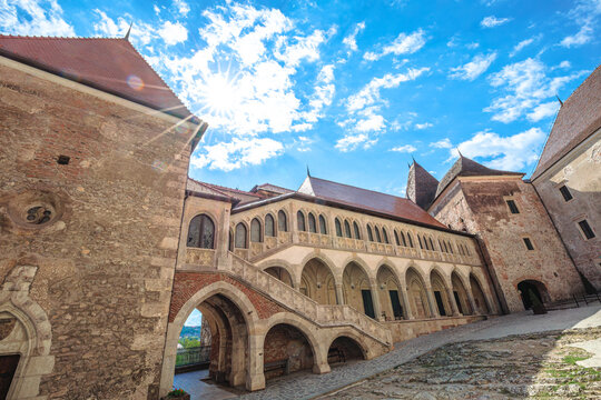 Corvin Castle, significant medieval landmark in Hunedoara, Romania. Presenting its gothic-renaissance architecture with arched courtyards and intricate stone details under vibrant sky in Transylvania