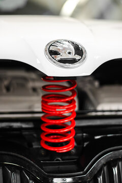 Krakow, Polska - September 06, 2026: Close up of glossy white vehicle front with chrome oval emblem Skoda and bright red coil spring above black mechanical components in automotive detail