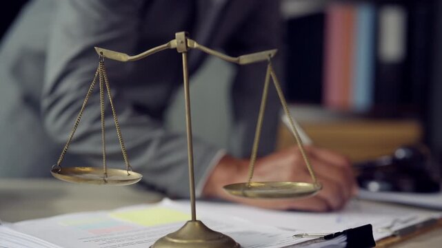 Legal Professional Signing Documents with Scales of Justice in Law Office